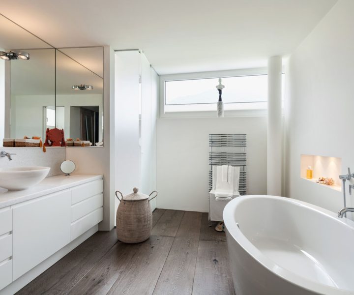 Minimalist White Bathroom Design Bright and airy bathroom design with white cabinetry, a large freestanding tub, and wooden floor, highlighting minimalistic decor and natural light.