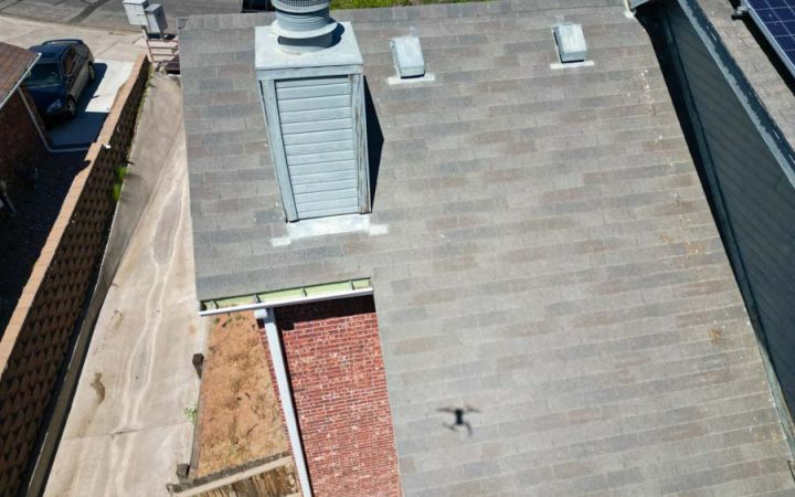 Efficient Roofing Solutions with Ventilation and Skylights Aerial view of a residential roof featuring multiple vents and a skylight, demonstrating advanced roofing techniques and equipment.