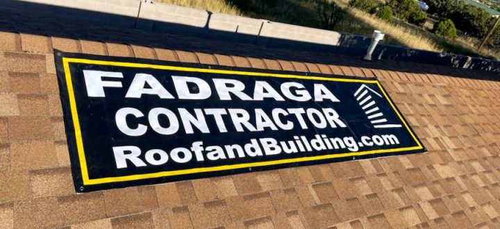 Fadraga Contractor Banner on Shingle Roof A Fadraga Contractor banner secured on a brown shingle roof, surrounded by a grassy field and nearby residential buildings.