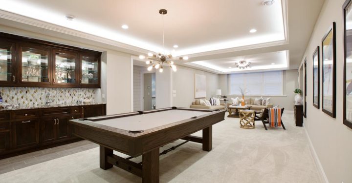 Elegant Game Room with Integrated Bar View of a spacious game room featuring a pool table, built-in dark wood bar cabinetry, and comfortable seating area, ideal for leisure and entertainment.