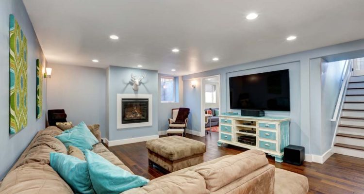 Cozy Lower Level Family Room A welcoming family room in the basement with a sectional sofa, teal and tan accents, and a central fireplace, ideal for family gatherings.