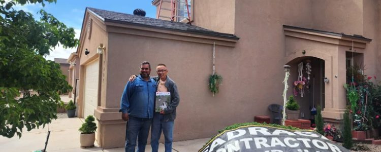 Contractor with Client Outside a Completed Project A contractor standing with a homeowner outside a beige house, with a Fadraga Contractor banner on the ground and a ladder leaning against the roof.